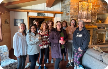 A group of women standing in front of a fireplace.