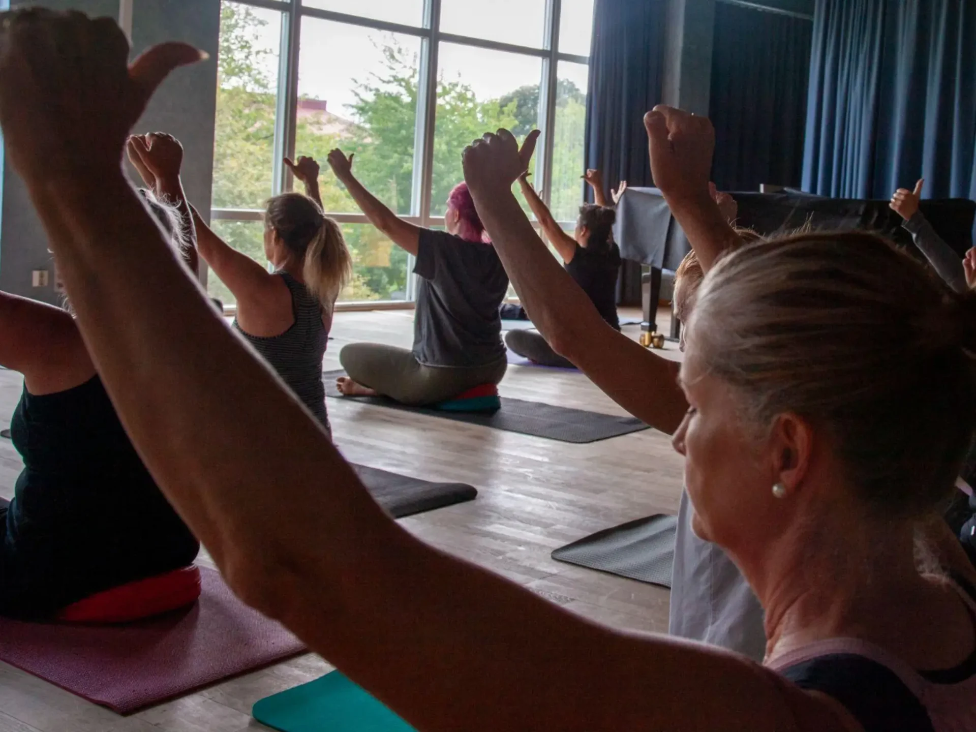 A group of people sitting in a room with their hands raised.